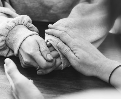 A photo of a young person's hands being held by a support worker.